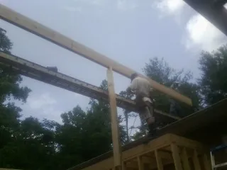 Carpenter setting a ridge beam over a new addition frame — Ice Dam Removal by Roofing Brothers in Baden