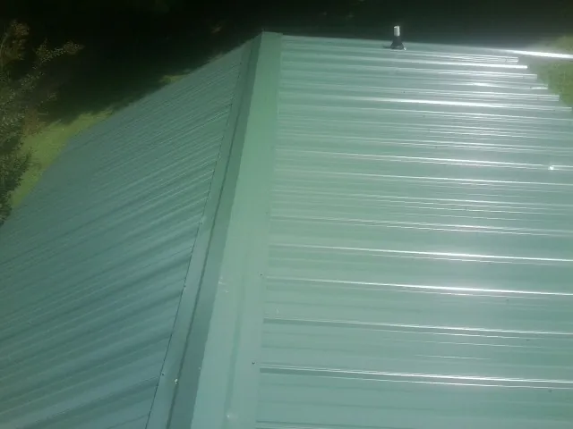 New green metal panels meeting at the ridge of a roof — Flat Roof Repair work by our crew in Baden