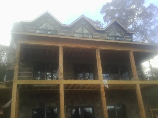 Dormers and porch framing on a large log home under construction — Roof Coating work by our crew in Baden