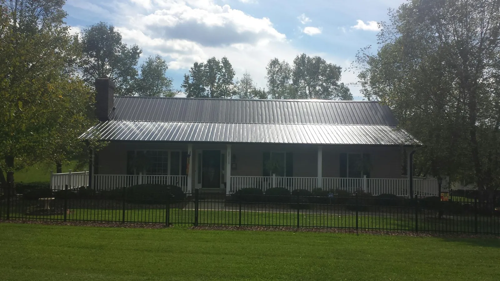 Gray metal roof on a brick ranch with a full width front porch — Gutter Guard Installation work by our crew in Baden