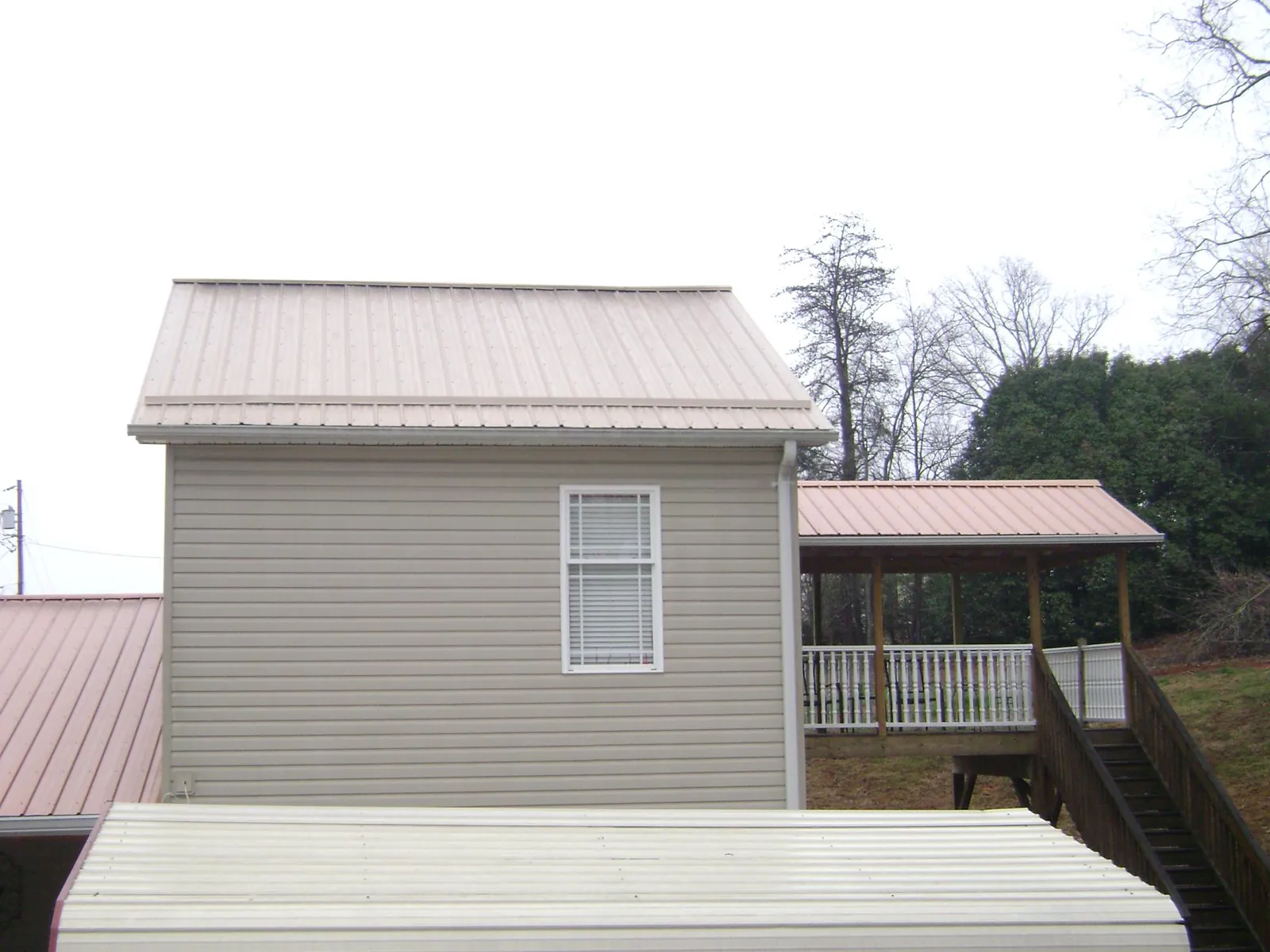 Tan metal roofs on a two story addition and attached porch, from a Roof Replacement job in Baden