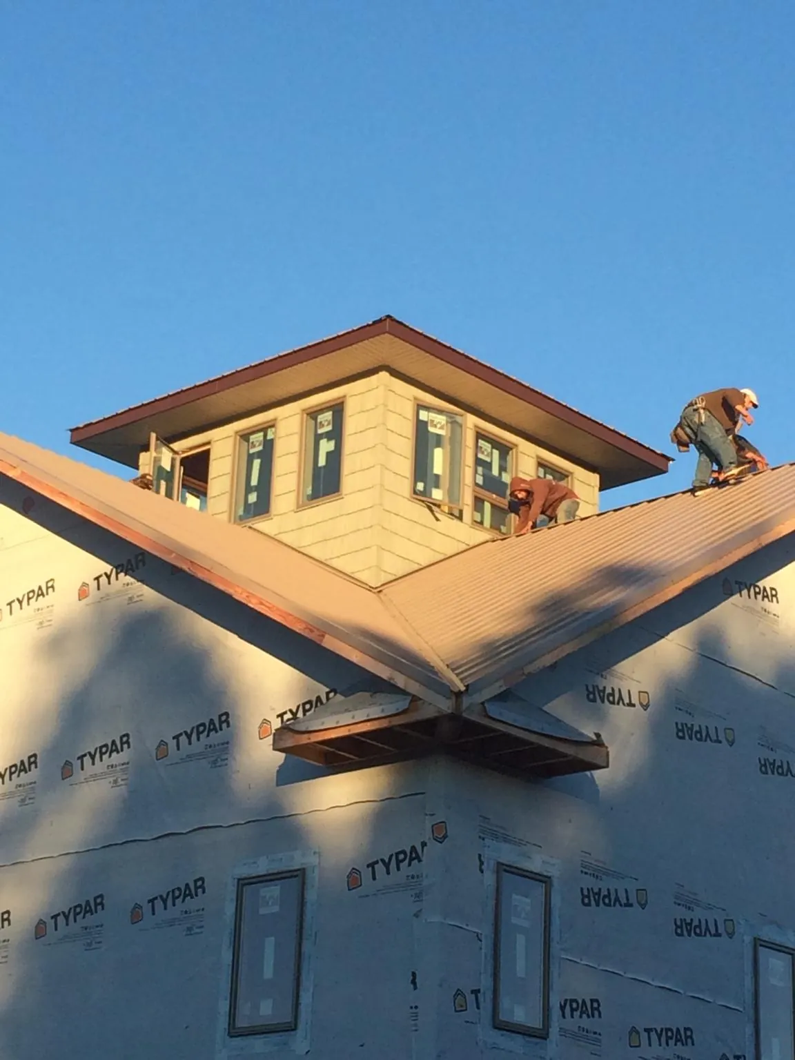Roofers working around a rooftop cupola on a new metal roof at sunset — Roof Waterproofing in Baden by Roofing Brothers